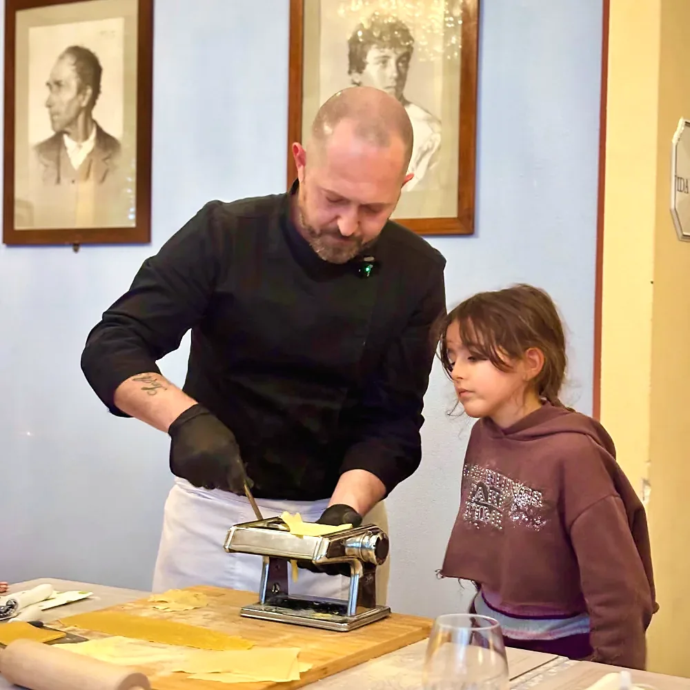 Chef and a young guest using the pasta machine together